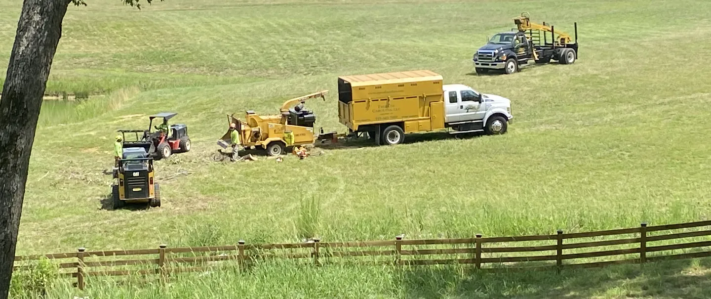 Yellow chip truck, chipper, loaders and a grapple truck working in a large field